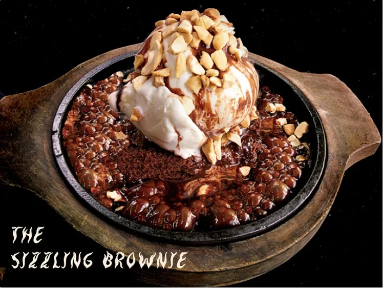 The Sizzling Brownie in a hot skillet with vanilla ice cream, chocolate sauce and nuts.