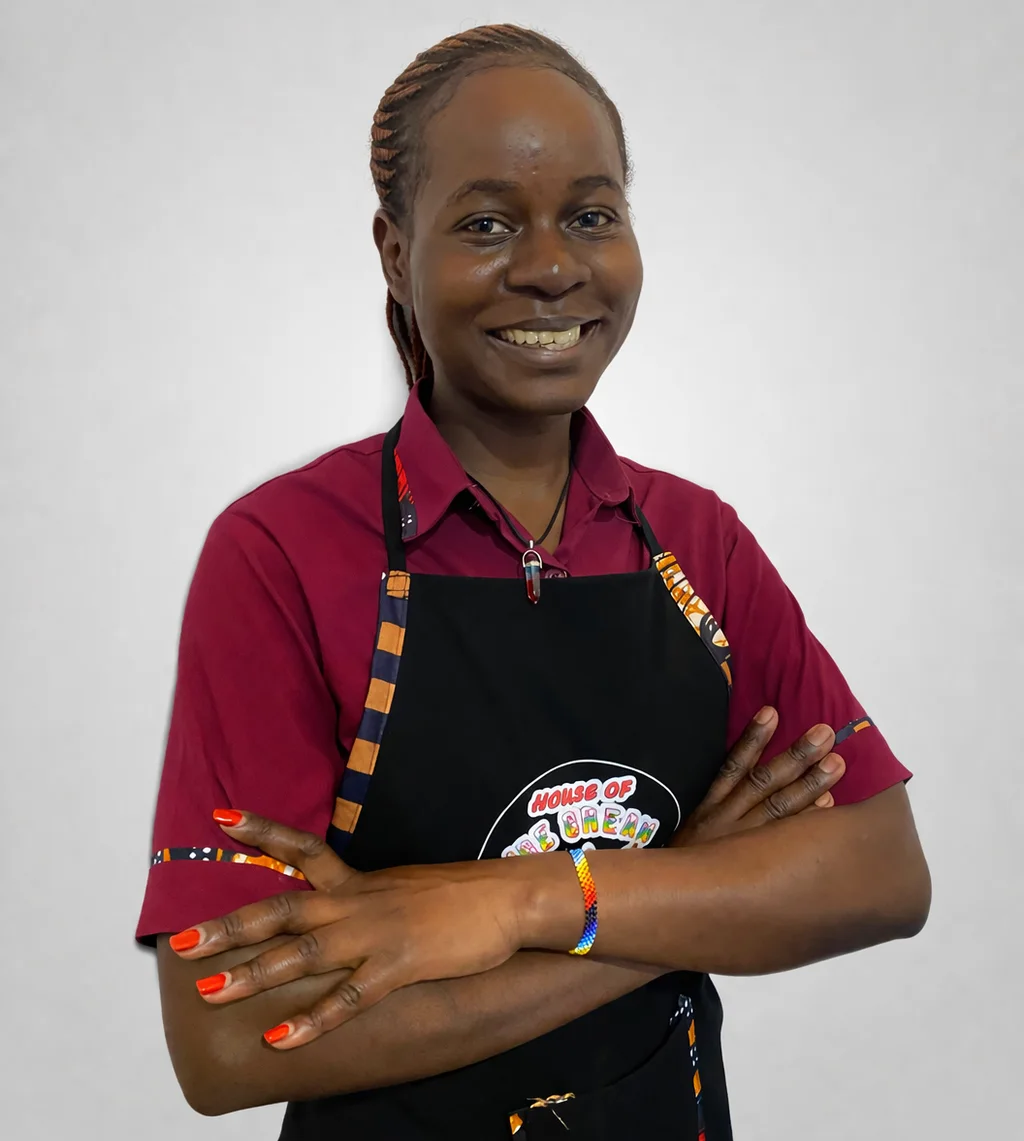 A House of Ice Cream team member smiling in a burgundy uniform and branded apron.