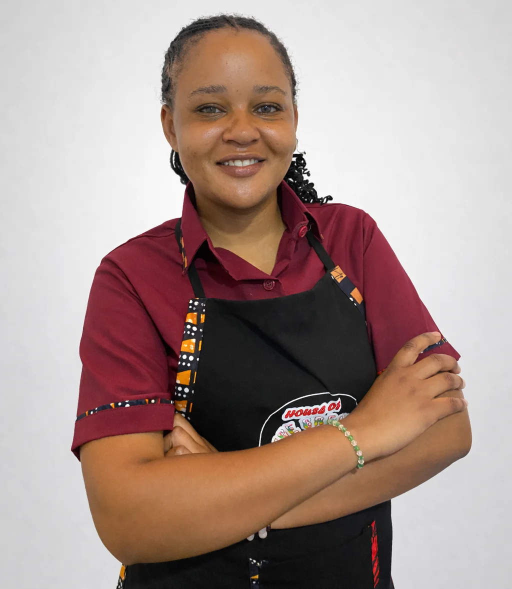 A House of Ice Cream team member smiling in a burgundy uniform and branded apron.