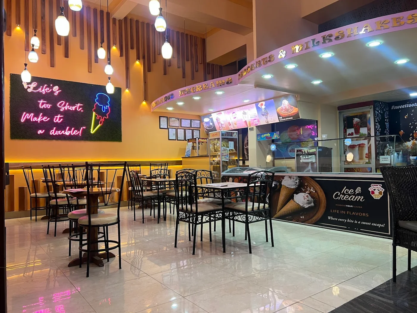 The current parlour interior with timber slats, orange walls, neon lettering and a glass dessert counter.